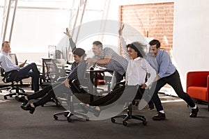 Carefree excited diverse office workers having fun riding oh cha