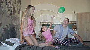 Carefree family in pajamas playing together on bed