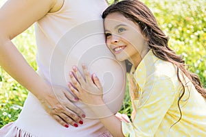 Carefree female child embracing her pregnant mother