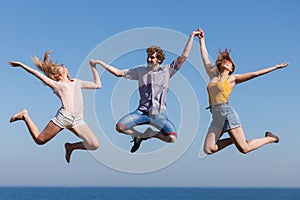 Carefree friends jumping by sea ocean water.