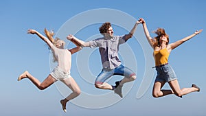 Carefree friends jumping on sky background.