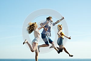 Carefree friends jumping on sky background.