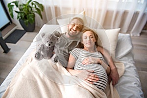 Carefree future parents playing with soft toy in bedroom