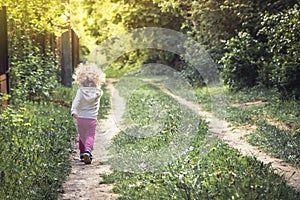 Carefree happy childhood with playful child walking alone on rural footpath in forest during summer holidays