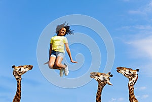 Carefree happy girl jump over giraffes heads