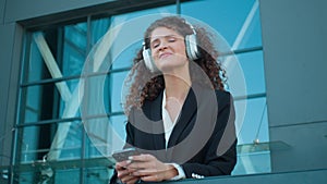 Carefree happy woman listen music in headphones mobile audio app online on phone Caucasian young girl businesswoman