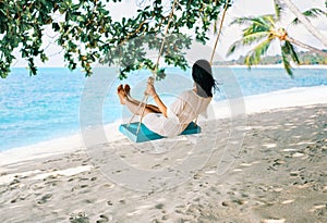 Carefree happy woman on swing on beautiful paradises beach