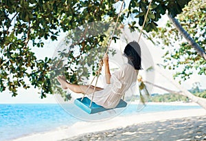 Carefree happy woman on swing on beautiful paradises beach