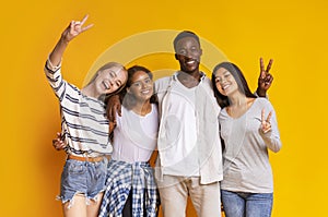 Carefree international students having fun over yellow background