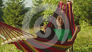 Carefree lovely asian female tourist in hammock enjoying music in headphones in mountain nature