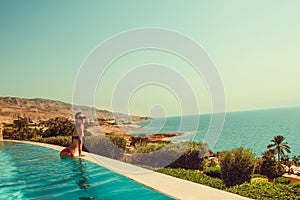 carefree model relaxing in luxurious infinity swimming pool. Young woman rest in spa resort. Summer luxury vacation. Tourism