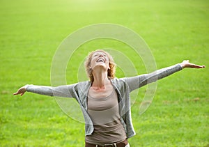 Carefree older woman smiling with arms open photo