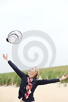 Carefree older woman throwing hat up with outstretched arms