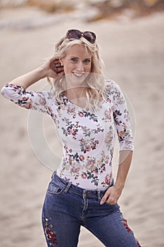 Carefree portrait, one young woman, 25 years old, floral pattern top, jeans. looking down, smiling joy