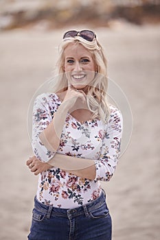 Carefree portrait, one young woman, 25 years old, floral pattern top, jeans. looking down, smiling joy.