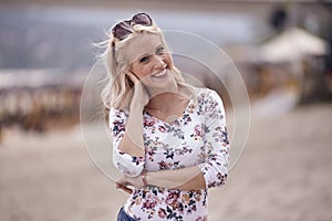 Carefree portrait, one young woman, 25 years old, floral pattern top, jeans. looking down, smiling joy.