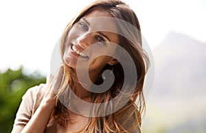 Carefree and positive. a woman enjoying the sunshine outdoors.