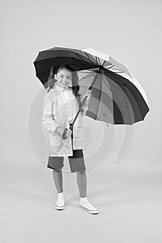 Carefree schoolgirl colorful umbrella wear waterproof rain coat. Autumn rain. Going to school rainy days more fun with