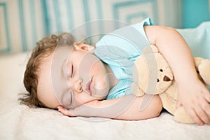 Carefree sleep baby with soft toy on bed