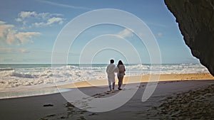 Carefree spouses stepping beach sand running away from ocean. Romantic couple