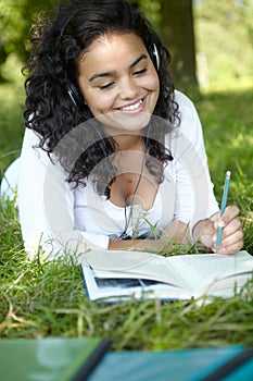 Carefree Student Revising And Listening To Music In Park