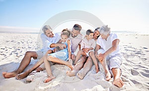 Carefree three generation family sitting together in the sand while spending time together at the beach. Loving parents