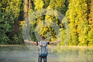 Carefree tourist with outstretched arms standing on the mountaing