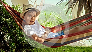 Carefree vacation as a little boy, donning a hat, enjoys the gentle rock of a garden hammock a heartwarming scene that