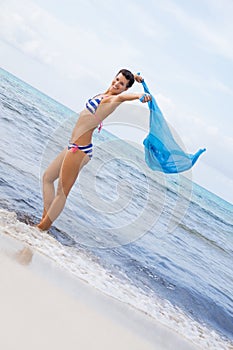 Carefree woman on a beach with a floating scarf