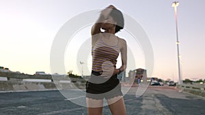 Carefree woman dancing outside in an urban setting at dusk. Beautiful young female fitness instructor preparing a