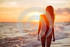 Carefree woman dancing in the sunset on the beach.