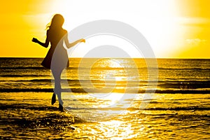 Carefree woman dancing in the sunset on the beach. vacation vita