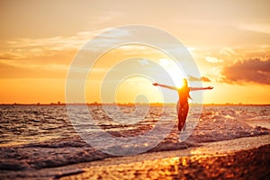 Carefree woman dancing in the sunset on the beach.