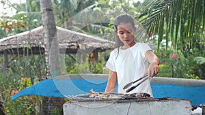 Carefree woman happily dancing while cooking fish in the garden.