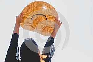 Carefree woman holding hat in sun,  close up. Summer vacation. Stylish young female holding straw hat in hands up in sky in