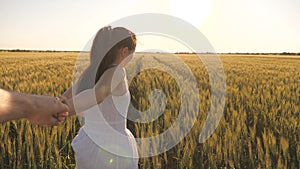 Carefree woman and man run across a wheat field holding hands in the summer sun. A family of farmers. A girl and a guy