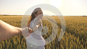 Carefree woman and man run across a wheat field holding hands in the summer sun. A family of farmers. A girl and a guy