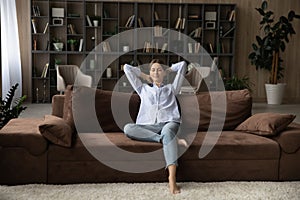 Carefree woman relaxing on comfy sofa in living room