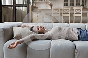 Carefree woman stretching lying on comfortable couch in living room