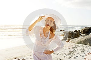 Carefree woman walking on beach with sun dress and hat