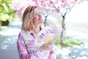 Carefree woman walking during Sakura in park with fan