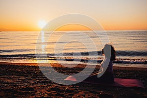 Carefree woman yoga practicing meditating by the sea sunrise time