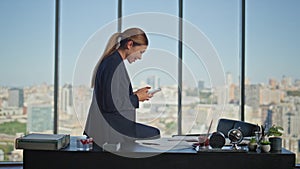 Carefree worker browsing smartphone in glass office. Smiling businesswoman rest