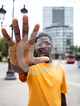 Carefree young African American man stretching his hand towards the camera in a city