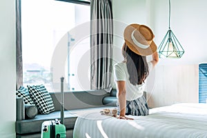 Carefree young Asian traveler female relax on bed in hotel room. Travel alone, summer , vacation concept. Copy space