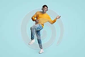 Carefree young black guy with wireless headset dancing
