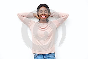 Carefree young black woman smiling with hands behind head against white background