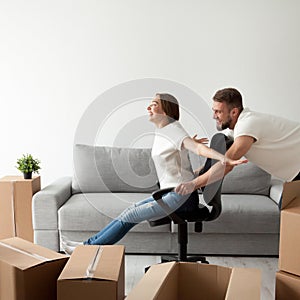 Carefree young couple having fun playing with office chair