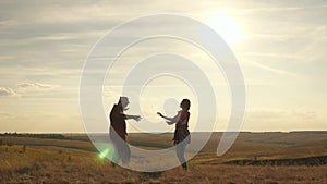 Carefree young girls and a man are dancing on field under the sun. Fun party at sunset. Happy woman and man dancing