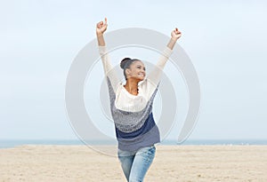 Carefree young woman with arms outstretched walking on the beach